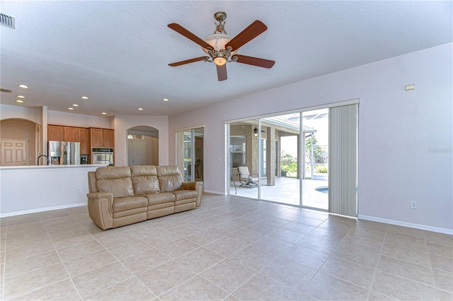 tiled living room featuring a textured ceiling and ceiling fan