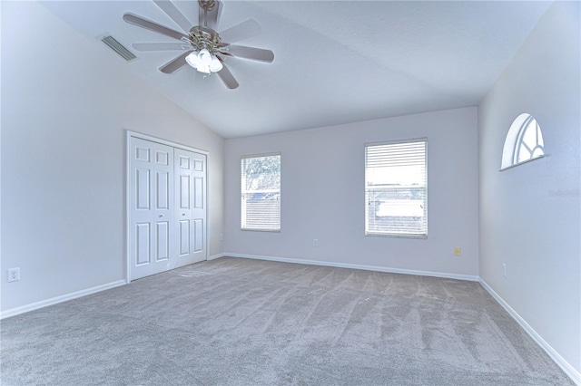 unfurnished bedroom featuring carpet, lofted ceiling, ceiling fan, and a closet