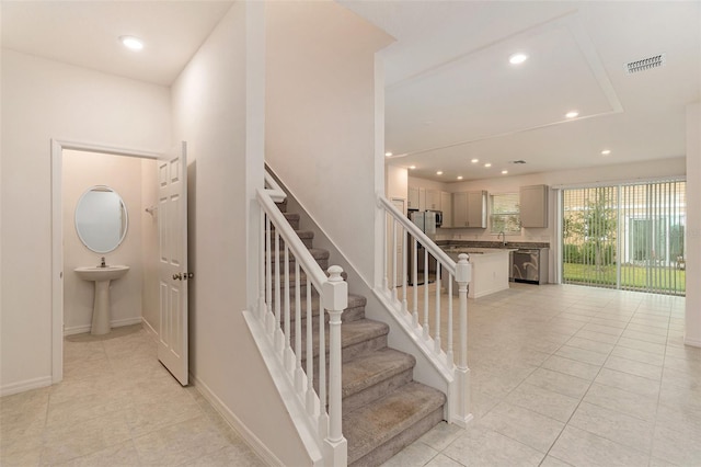 stairs with tile patterned floors and sink