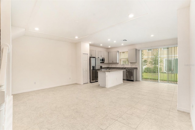 kitchen with stainless steel appliances, light tile patterned floors, sink, gray cabinets, and a kitchen island