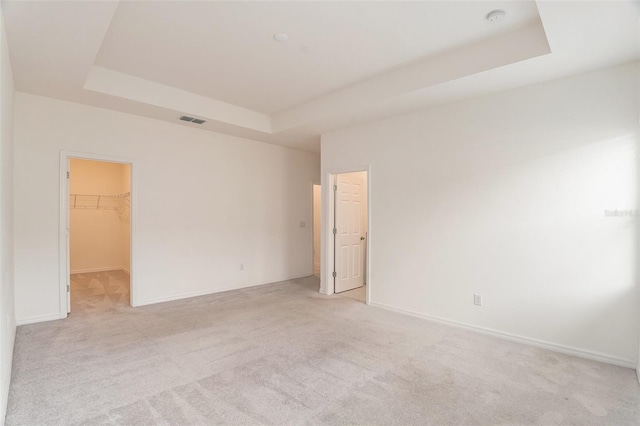 empty room featuring light colored carpet and a tray ceiling