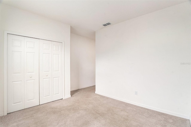 unfurnished bedroom featuring light carpet and a closet