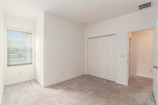 unfurnished bedroom with light carpet and a closet