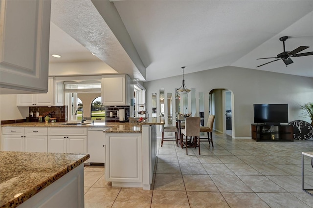 kitchen with dishwasher, dark stone counters, hanging light fixtures, sink, and white cabinetry