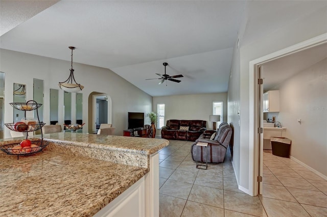 kitchen with ceiling fan, light tile patterned floors, pendant lighting, and lofted ceiling