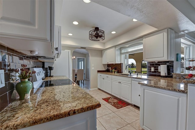 kitchen with white cabinets, stone countertops, white appliances, and sink