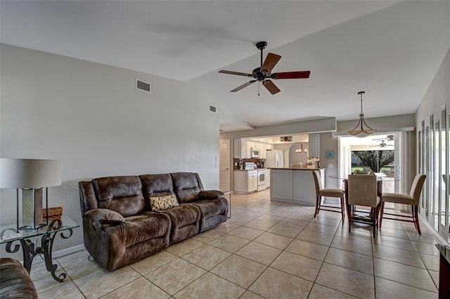 living room with ceiling fan, light tile patterned floors, and vaulted ceiling