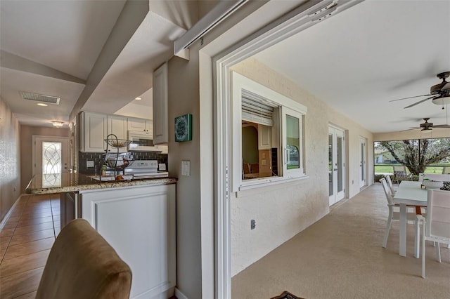 interior space featuring tasteful backsplash, light stone counters, white range, vaulted ceiling, and ceiling fan