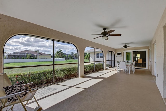 unfurnished sunroom featuring ceiling fan