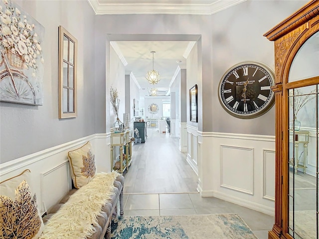 hall with a chandelier, crown molding, and light tile patterned flooring