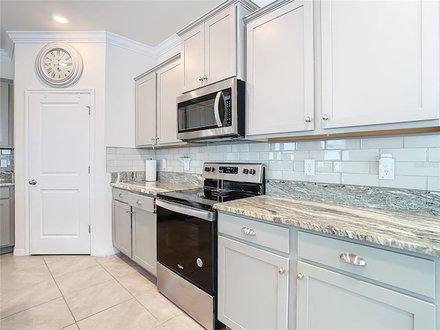 kitchen with stainless steel appliances, backsplash, crown molding, gray cabinets, and light tile patterned floors