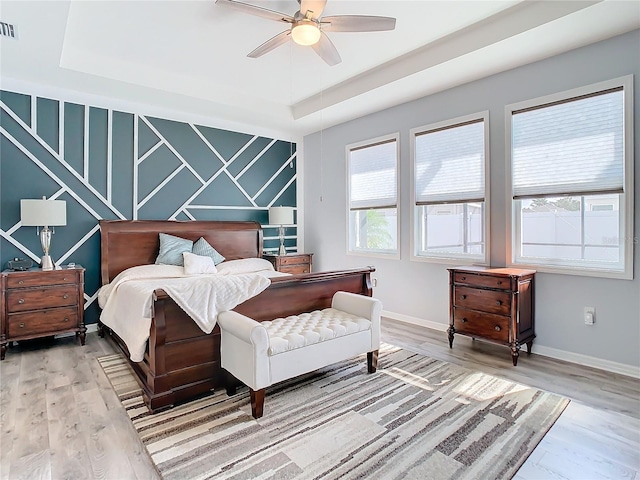 bedroom featuring hardwood / wood-style floors, ceiling fan, and a tray ceiling