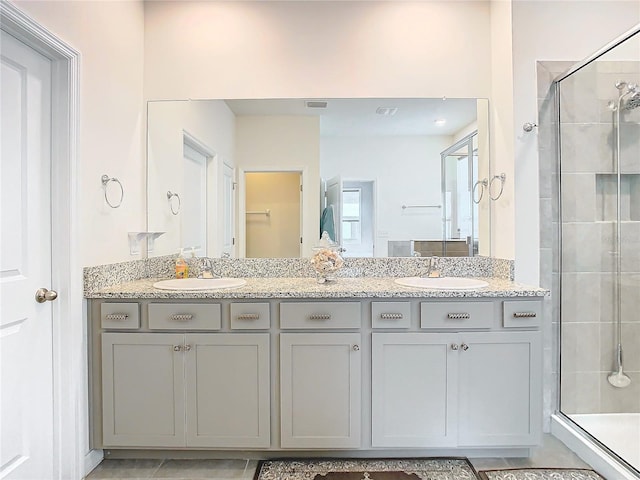 bathroom with tile patterned flooring, vanity, and a shower with door