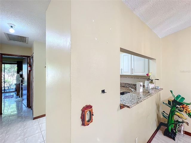 kitchen featuring light tile patterned floors, a textured ceiling, lofted ceiling, and sink