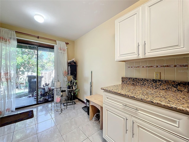 interior space with tasteful backsplash, white cabinetry, light tile patterned floors, and light stone countertops