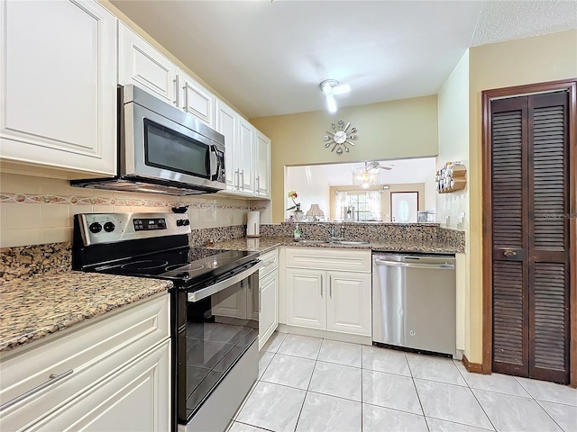 kitchen with white cabinets, sink, appliances with stainless steel finishes, tasteful backsplash, and light tile patterned flooring