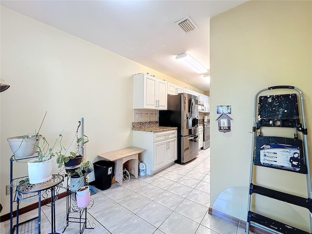 kitchen featuring white cabinets, stainless steel refrigerator with ice dispenser, tasteful backsplash, and light tile patterned flooring