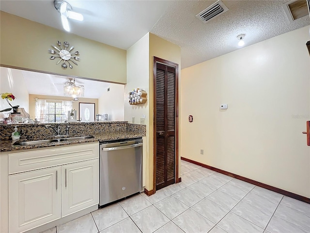 kitchen with dark stone counters, white cabinets, sink, stainless steel dishwasher, and a textured ceiling