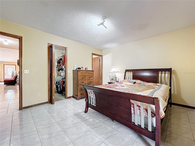 tiled bedroom with a walk in closet, a closet, and a textured ceiling