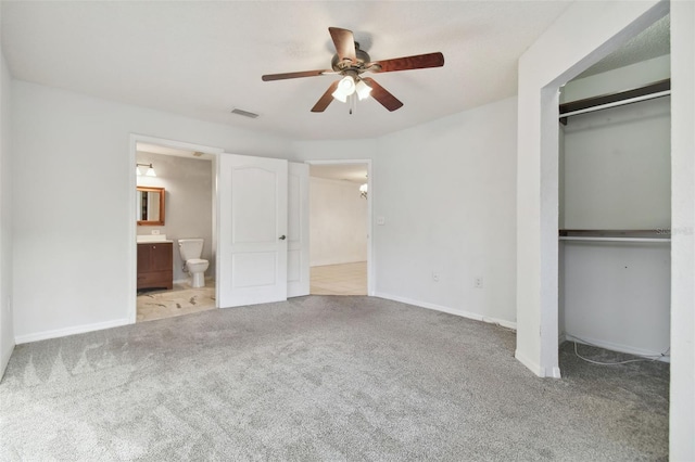 unfurnished bedroom featuring carpet flooring, ensuite bathroom, ceiling fan, and a closet