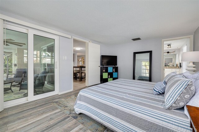 bedroom with access to outside, wood-type flooring, and a textured ceiling