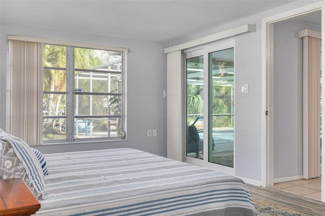 bedroom featuring light hardwood / wood-style floors, access to exterior, and a textured ceiling