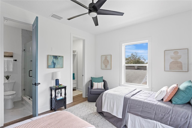 bedroom featuring visible vents, ceiling fan, ensuite bath, wood finished floors, and baseboards