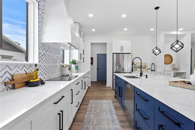 kitchen with light stone countertops, premium range hood, hanging light fixtures, and white cabinetry