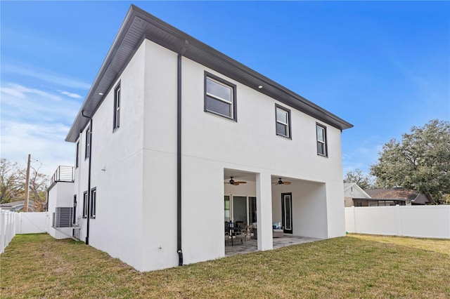 rear view of property with a yard, stucco siding, a patio area, ceiling fan, and a fenced backyard