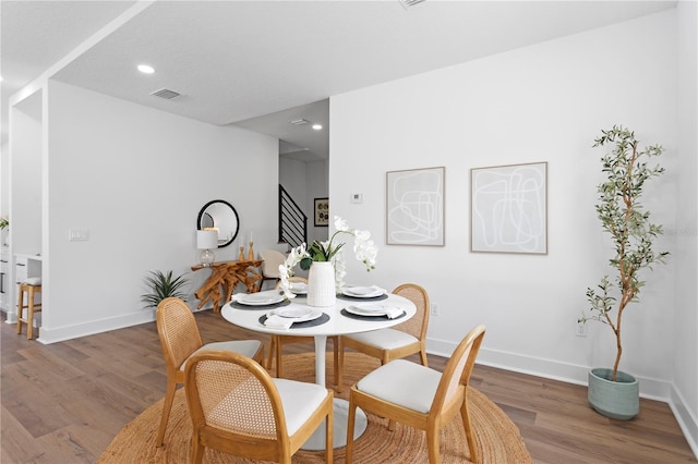 dining room featuring recessed lighting, wood finished floors, visible vents, baseboards, and stairs