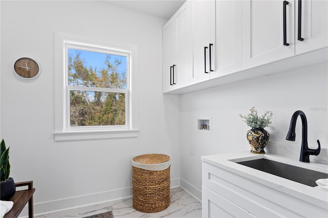 laundry area featuring washer hookup, a sink, baseboards, marble finish floor, and cabinet space