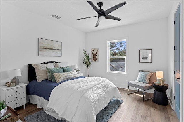 bedroom featuring visible vents, ceiling fan, baseboards, and wood finished floors