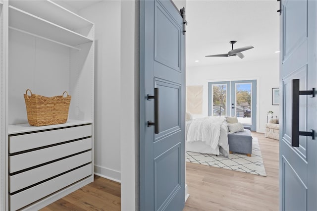 interior space featuring french doors, a barn door, light wood-style flooring, and a ceiling fan