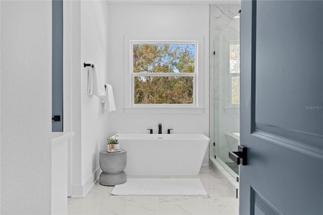 full bathroom with marble finish floor, a shower stall, baseboards, and a freestanding tub