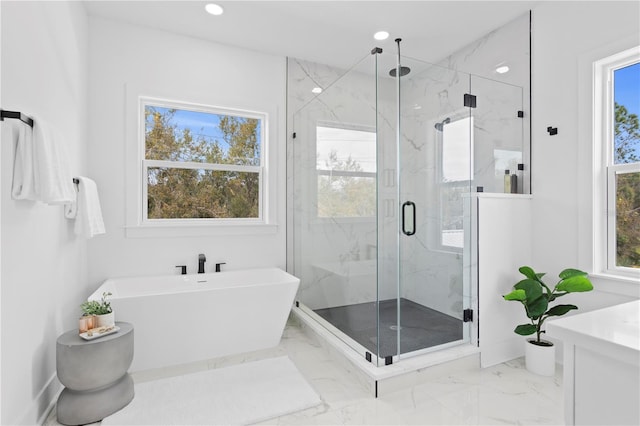 bathroom with marble finish floor, a marble finish shower, recessed lighting, vanity, and a freestanding tub