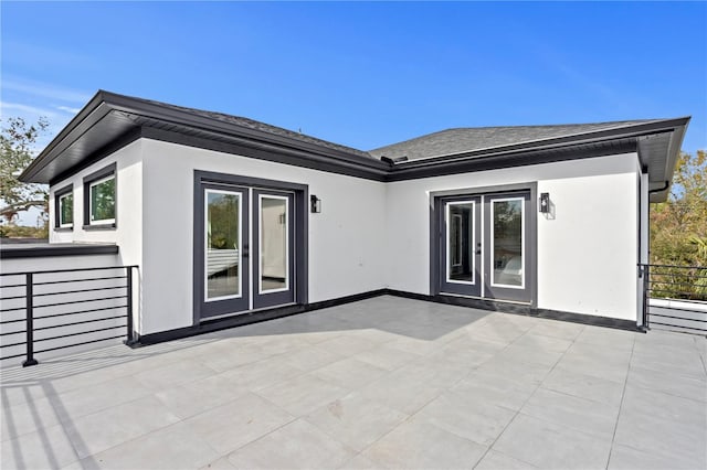 back of house featuring french doors, roof with shingles, a patio, and stucco siding