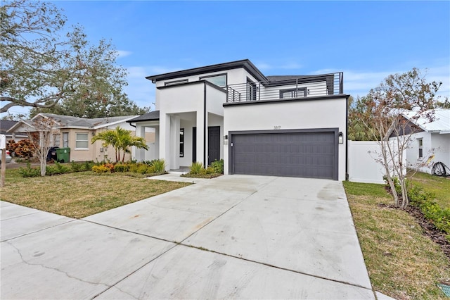 contemporary house with concrete driveway, a balcony, fence, a front lawn, and stucco siding