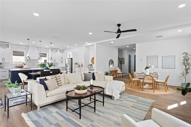 living room featuring ceiling fan, light wood-type flooring, stairs, and recessed lighting