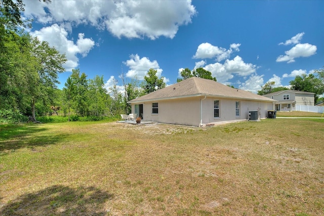 rear view of property with cooling unit and a yard