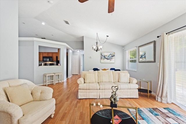 living room featuring ceiling fan with notable chandelier, light hardwood / wood-style flooring, and lofted ceiling