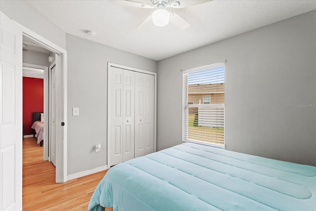 bedroom with ceiling fan, a closet, wood-type flooring, and a textured ceiling