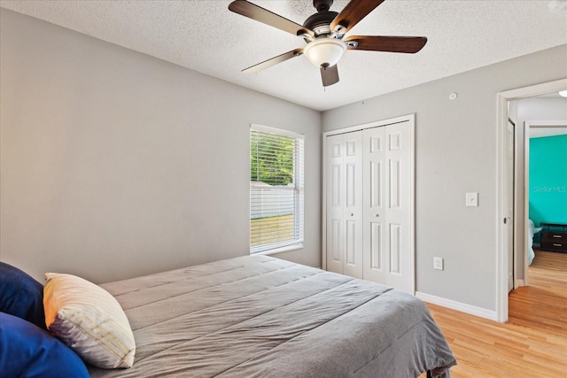 bedroom with a textured ceiling, light wood-type flooring, a closet, and ceiling fan