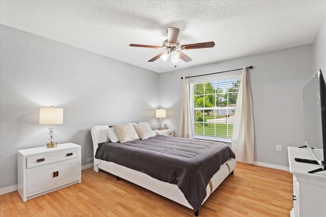 bedroom featuring ceiling fan, light hardwood / wood-style flooring, and a textured ceiling