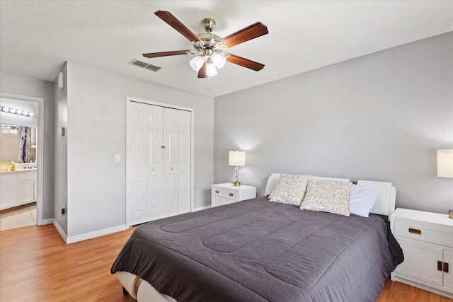 bedroom featuring ensuite bathroom, a textured ceiling, ceiling fan, light hardwood / wood-style flooring, and a closet