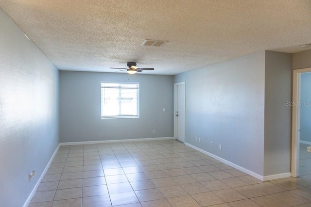 empty room featuring a textured ceiling, light tile patterned flooring, and ceiling fan