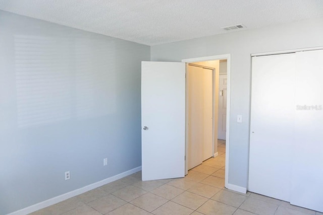 tiled empty room with a textured ceiling