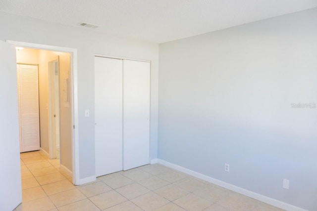 unfurnished bedroom with a closet and light tile patterned flooring