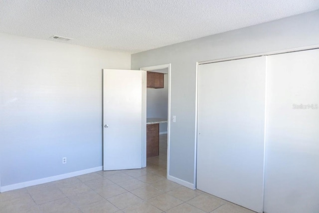 unfurnished bedroom featuring light tile patterned floors, a textured ceiling, and a closet