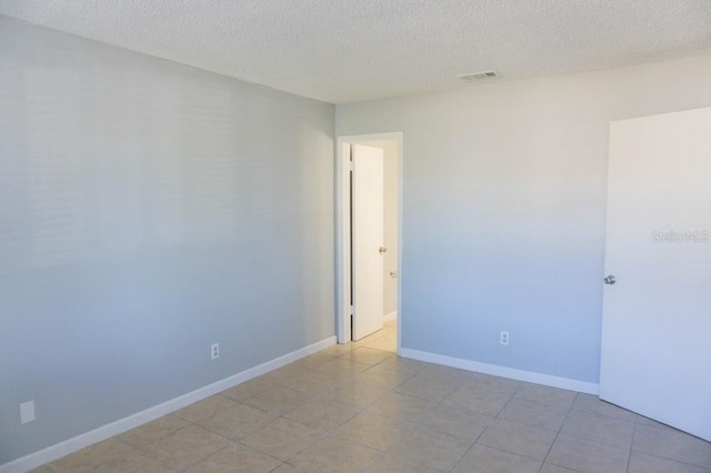 tiled spare room with a textured ceiling