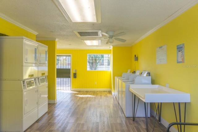 laundry area featuring ceiling fan, a textured ceiling, wood-type flooring, stacked washer / dryer, and crown molding